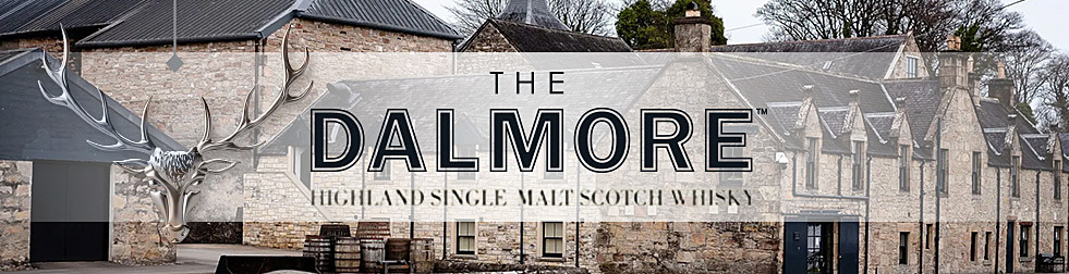 A photograph of The Dalmore distillery exterior; stone farmhouse-style building and casks on a grass patch. Superimposed text reads: The Dalmore Highland Single Malt Scotch Whisky.