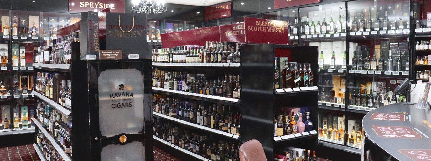 A shop counter with seats and a display of whisky bottles in the background.