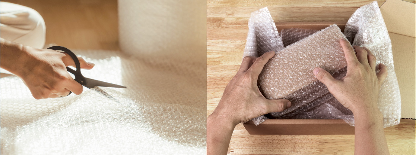 A person packaging a bottle of whisky for shipping in a cardboard box with bubble wrap and packaging material
